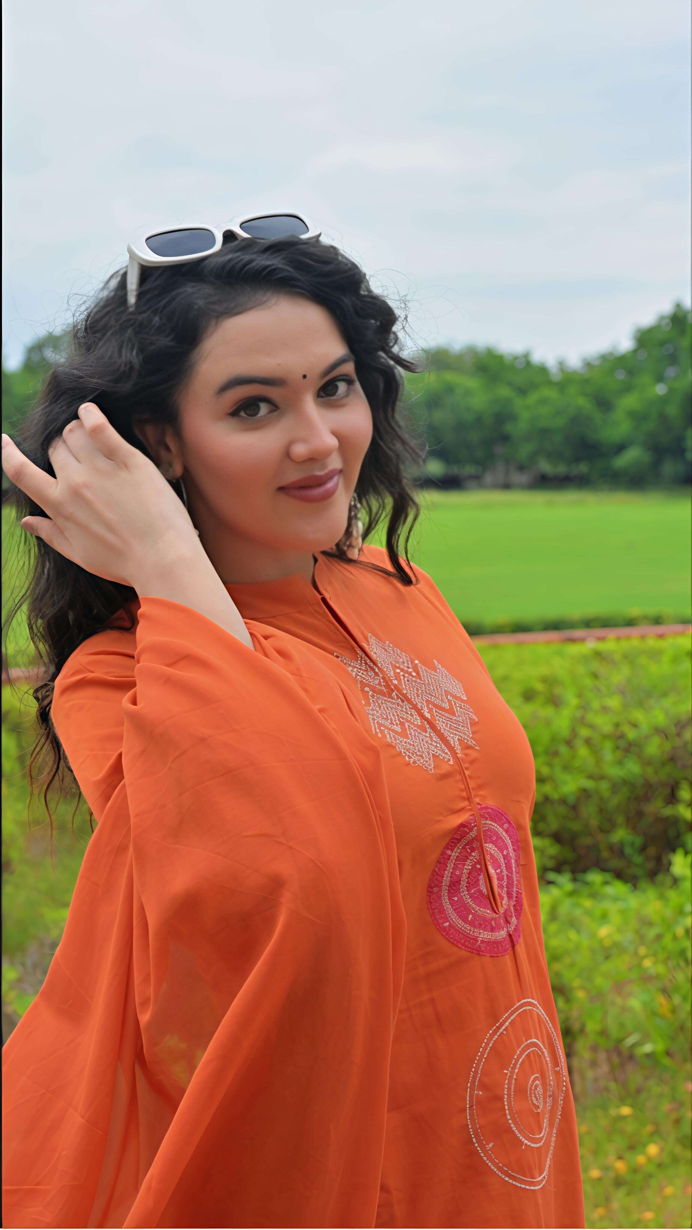 Elegant woman wearing an orange cotton kurta set with beautiful embroidery in a natural setting