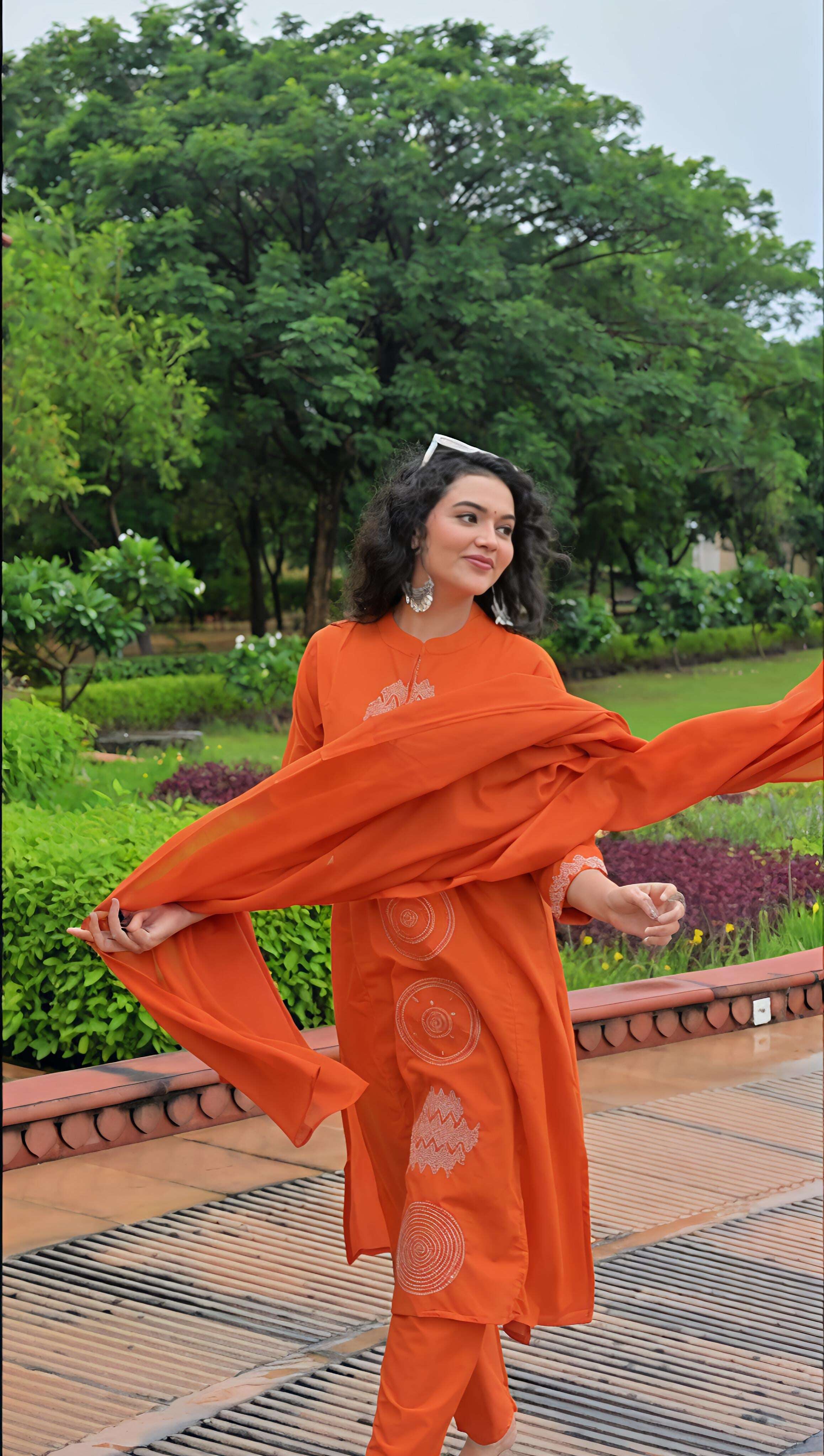 Woman wearing an orange cotton kurta set with elegant patterns in a scenic garden setting