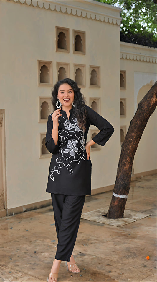 Elegant women's embroidered kurta set in black with intricate floral designs and matching black pants